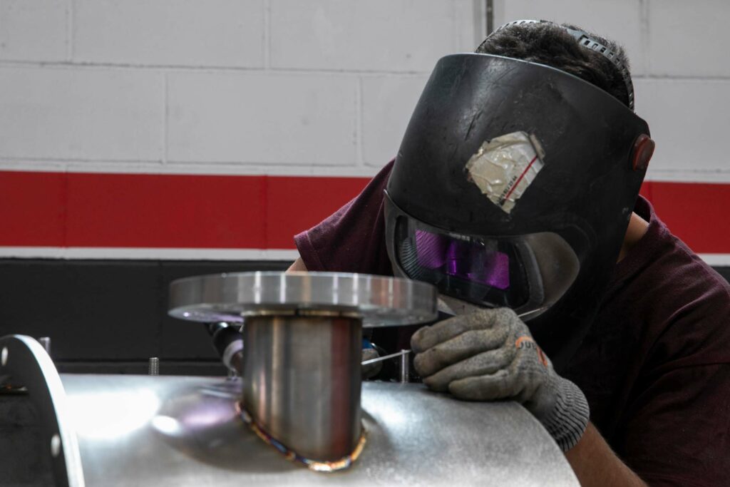 Soldador realizando una unión TIG en acero inoxidable con casco protecto