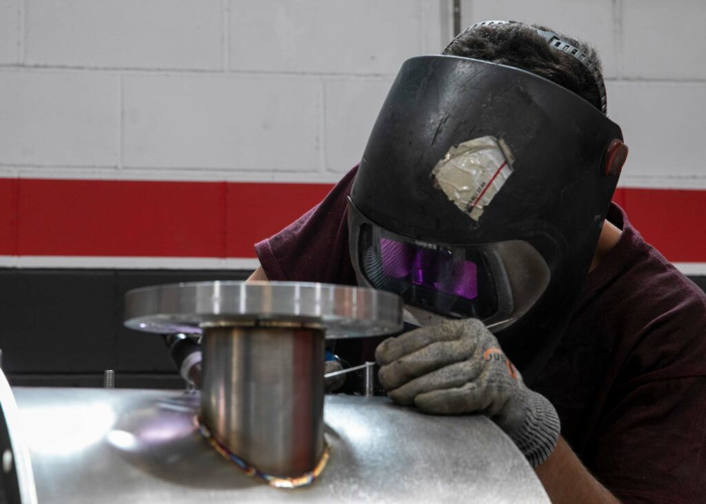TIG welder making a TIG joint in stainless steel with protective helmet